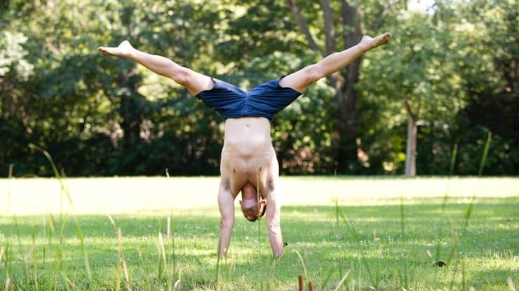 Handstand Push-Up Progression: Training for Advanced Power & Control 1 man performs straddle handstand outdoors