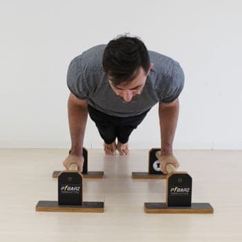 The Benefits of Parallettes Training and How to Overcome Challenges 2 Ryan doing a push up on parallettes