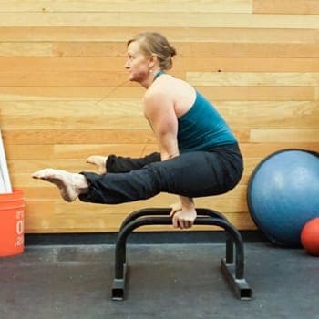 How to Build Your Own Parallettes (And the Best Options Money Can Buy) 1 Sidney doing a straddle sit exercise on parallettes