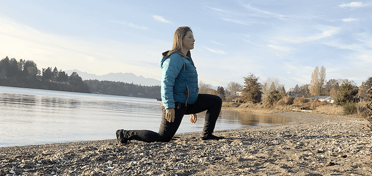 woman doing lunge stretch on beach
