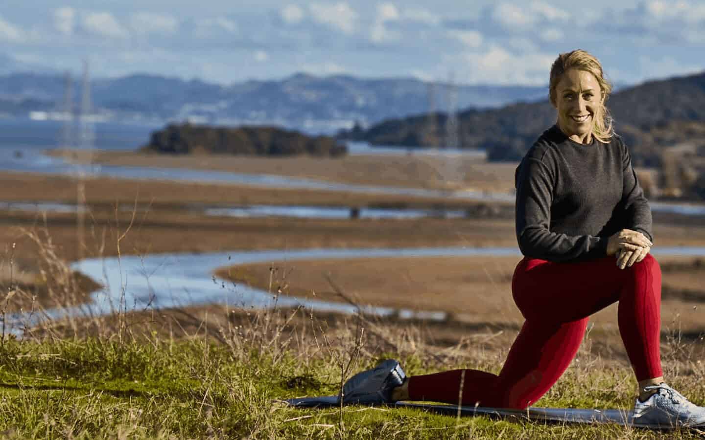 Juliet Starrett is casually pretending to stretch on a yoga mat in a natural setting
