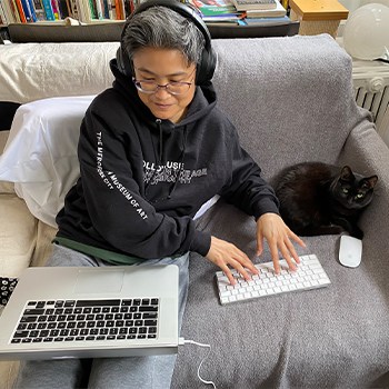 Fixing 30 Years of Deskbod: How this Graphic Designer Loosened Painful Joints and Got Strong 2 Kamomi working on her couch while her cat stares at the camera