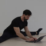 GMB Head Coach Ryan Hurst in pancake stretch working on laptop