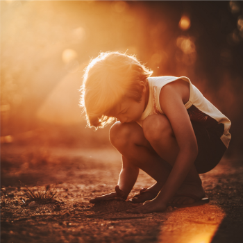 Child squatting down playing in sand
