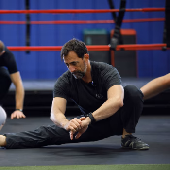 A man moving through a Cossack squat as a burpee variation