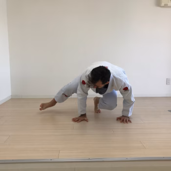Train Hard, Recover Smarter: What the Best Grapplers Are Doing in 2025 to Keep Rolling Hard Into Their 40s and Beyond 1 Man performing monkey locomotion exercise in a BJJ gi